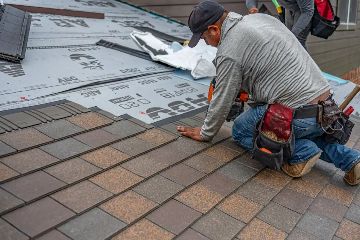 Roofing installer fastening shingles over new underlayment in El Monte, CA
